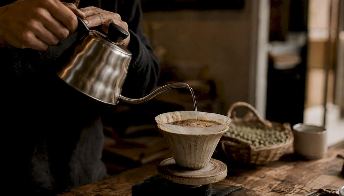 Hands pouring water over coffee grounds