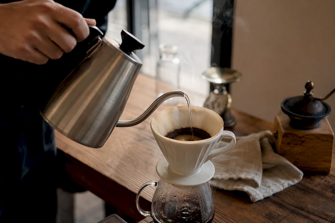 Hands pouring coffee with gooseneck kettle